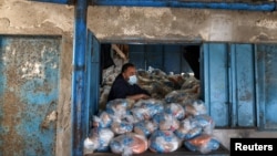 Seorang pekerja Palestina mempersiapkan bantuan pangan di sebuah pusat distribusi yang dikelola oleh Badan PBB untuk Urusan Pengungsi Palestina di kamp Beach, Kota Gaza, Rabu, 7 April 2021. 