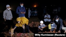 Seorang perempuan dan anak-anaknya saat pemakaman suaminya yang meninggal akibat COVID-19 di Bekasi, 27 Juli 2021. (Foto: Willy Kurniawan/Reuters)