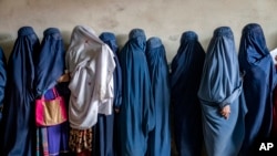 FILE - Afghan women wait for food distributed by a humanitarian aid group, in Kabul, Afghanistan, May 23, 2023. U.S. Secretary of State Antony Blinken has announced new programs to empower Afghan women in Afghanistan. 