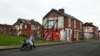 FILE - A woman pushes a stroller along a semi-derelict street in the Gresham area of Middlesbrough, northern Britain, Jan. 20, 2016. Asylum seekers in the northern English town of Middlesbrough are often suffering abuse.