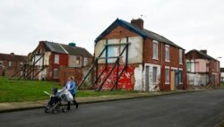 Seorang wanita mendorong kereta bayi di sepanjang jalan bertingkat semi-telantar di daerah Gresham di Middlesbrough, Inggris utara, 20 Januari 2016. (Foto: Reuters)