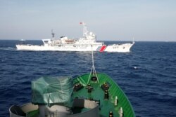 FILE - A ship (top) of the Chinese Coast Guard is seen near a ship of the Vietnam Marine Guard in the South China Sea, about 210 km ff shore of Vietnam May 14, 2014.
