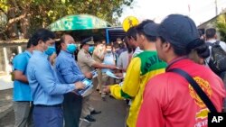 FILE: In this Jan. 27, 2020, photo provided by the Poipet International Checkpoint, government officials distribute face masks to tourists during a launch of a plan to distribute a million masks to travelers arriving at the checkpoint with Thailand as a safety precaution against 