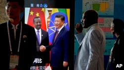 Delegasi Afrika berjalan melalui layar panel yang menampilkan rekaman video pertemuan Presiden China, Xi Jinping dengan Perdana Menteri Ethiopia, Abiy Ahmed menjelang berlangsungnya Forum Kerjasama China-Afrika di Beijing, 3 September 2018.