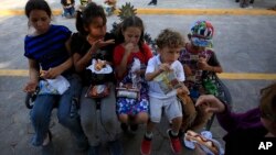 Anak-anak migran menyantap makanan yang disediakan oleh badan amal di Texas, di jembatan internasional Puerta Mexico, Matamoros, negara bagian Tamaulipas, Meksiko, 27 Juni 2019. 