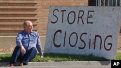 盐湖城，“欧洲珍宝”古董店店主埃文斯坐在他的“商店关门”标志旁（2020年5月8日）。