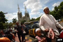 Warga muslim terlihat berjalan menuju ke Masjid Istiqlal dengan latar belakang Gereja Katedral Jakarta pada 29 Maret 2013. (Foto: AFP)