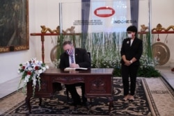 Menteri Luar Negeri AS Mike Pompeo menandatangani buku tamu saat Menteri Luar Negeri Retno Marsudi berdiri sebelum pertemuan mereka di Jakarta. (Foto: Courtesy/Kemenlu RI)