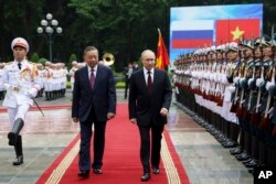 Presiden Rusia Vladimir Putin (tengah) bersama Presiden Vietnam To Lam memeriksa barisan pengawal kehormatan saat upacara penyambutan resmi di Istana Kepresidenan Vietnam, di Hanoi, Kamis, 20 Juni 2024. (Gavriil Grigorov, Sputnik, Kremlin Pool Photo via AP)