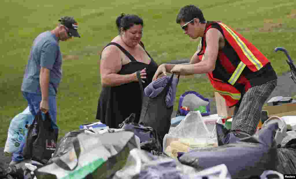 A volunteer gives clothes to a woman who was evacuated from her home after the train explosion in Lac Megantic, Quebec, July 7, 2013.