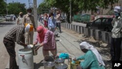 Para relawan mendistribusikan makanan kepada para keluarga miskin di tengah karantina wilayah di yang diberlakukan di Dwarka, New Delhi, India, pada 12 April 2020. (Foto: AP)