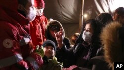 Migrants talk with Belarusian Red Cross employees in the logistics center in the checkpoint "Bruzgi" at the Belarus-Poland border near Grodno, Nov. 30, 2021.