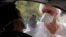 A medical worker administers a nasal swab to a patient at a drive-through testing site for coronavirus disease (COVID-19) near the hospital in Laval, France, July 15, 2020.