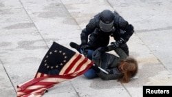 Seorang polisi menahan seorang demonstran pro-Trump sementara massa menyerbu gedung parlemen AS, Capitol, untuk memprotes hasil pilpres 2020, di Washington DC, Rabu, 6 Januari 2021.(Foto: Reuters)