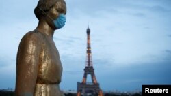 Zlatna statua sa zaštitnom maskom na licu na Trgu Trokadero, u blizini Ajfelove kule u Parizu (Foto: Reuters/Benoit Tessier)