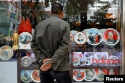 2017年10月21日，在北京举行的中共第十九届全国代表大会期间，北京一家商店展示的带有中国前国家主席毛泽东和中国国家主席习近平形象的纪念盘。