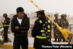 Kazakhstan - A police officer checks the identity card of a man as security forces keep watch in a street in Kashgar, Xinjiang Uighur Autonomous Region, China, March 24, 2017. REUTERS/Thomas Peter/File Photo