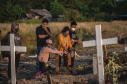 Anggota keluarga memberikan penghormatan terakhir saat pemakaman orang terkasih yang meninggal karena COVID-19 di sebuah pemakaman di Surabaya pada 9 Agustus 2021. (Foto: AFP/Juni Kriswanto)