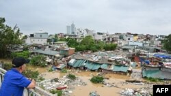 Seorang pria berdiri di Jembatan Long Bien Bridge dan mengamati rumah-rumah yang sebagian terendam air banjir setelah disapu Topan Yagi di Hanoi, Vietnam, Selasa, 10 September 2024. (Foto: Nhac Nguyen/AFP)