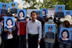 In this file photo taken on July 29, 2020, Rong Chhun, president of Cambodia's Independent Teachers' Association, stands with protesters holding placards of Cambodia's Prime Minister Hun Sen and his wife Bun Rany as they call for benefits to help workers after their textile factory was shuttered amidst the economic downturn related to the COVID-19 coronavirus pandemic in Phnom Penh, Cambodia. (Photo by TANG CHHIN Sothy/AFP)