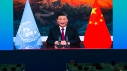 Media staff members watch a live image of China's President Xi Jinping speaking at the media center of the UN Biodiversity Conference (COP 15) in Kunming, in China's southwestern Yunnan province on Oct. 12, 2021.