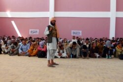 Seorang pejuang Taliban melakukan penjagaan terhadap anggota pasukan keamanan Afghanistan yang menyerah di kota Ghazni, barat daya Kabul, Afghanistan, setelah Taliban berhasil menguasai wilayah selatan negara itu. (Foto: AP)