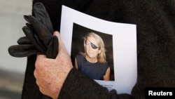 FILE - A man holds a sign honoring Sunday Times journalist Marie Colvin after a memorial service, outside St Martin in the Field in London, May 16, 2012. 