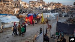 ជនជាតិប៉ាឡេស្ទីនដើរតាមផ្លូវនៃកន្លែងដែលត្រូវបានបំផ្លាញដោយការវាយប្រហាររបស់អ៊ុយក្រែននៅហ្កាហ្សាកាលពីថ្ងៃទី១១ កុម្ភៈ ឆ្នាំ២០២៥។