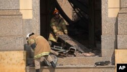 Dua petugas pemadaam kebakaran memindahkan puing-puing pasca kebakaran yang menghanguskan Museum Nasional Brazil di Rio de Janeiro, Senin (3/9). 