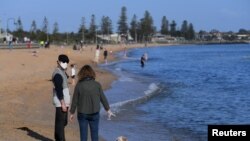 Orang-orang menikmati sinar matahari, ketika negara bagian Victoria mulai melonggarkan pembatasan Covid-19, di pantai Elwood di Melbourne, Australia, 14 September 2020. (Foto: Reuters)