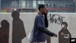 Seorang pria menggunakan tangan untuk menutup mulut dan hidung saat berjalan di Johannesburg, Afrika Selatan, Senin, 16 Maret 2020. (Foto: AP)