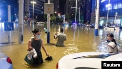 中国安徽合肥的民众在被洪水淹没的街道上过马路。（2020年6月27日）