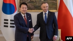Presiden Korea Selatan Yoon Suk Yeol dan Presiden Polandia Andrzej Duda berjabat tangan usai pertemuan di Warsawa hari Kamis (13/7). 
