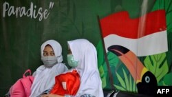 Dua pelajar berbincang sambil mengenakan masker di tengah pandemi virus corona di Banda Aceh, 10 Juni 2020. (Foto: AFP)
