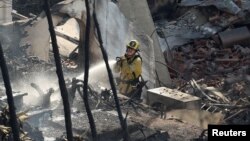 A firefighter sprays water in a burned house following the Palisades Fire at the Pacific Palisades neighborhood in Los Angeles, Jan. 10, 2025.