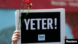 A member of the Journalists Union of Turkey (TGS) holds a placard reading "Enough!" during a demonstration to mark World Press Freedom Day in central Istanbul, Turkey, May 3, 2017.