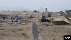 Dua orang perempuan tampak berjalan di jalanan dekat kamp pengungsi di dekat perbatasan antara Rafah dan Mesir, pada 22 Mei 2024. (Foto: AFP/Eyad Baba)