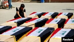 FILE - A man sits next to coffins holding the remains of Yazidis killed in Islamic State attacks in 2014, after they were exhumed from a mass grave in Mosul, Iraq, June 20, 2023. Germany said on April 10, 2024, it arrested an Iraqi couple accused of genocide against the Yazidis.