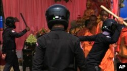 Security officers try to beat Buddhist monks who took part in a rally of the Cambodian National Rescue Party in Phnom Penh, Cambodia, Saturday, Jan. 4, 2014.