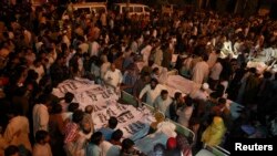 Pakistani relatives gather beside the covered bodies of victims who were killed in suicide bomb attack in Wagah border near Lahore, Nov. 2, 2014. 