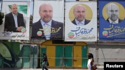 Warga berjalan melewati spanduk calon presiden Mohammad Bagher Ghalibaf yang dipajang di sebuah jalan di Teheran, Iran, Kamis 27 Juni 2024.