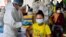 FILE - Health officials in personal protective equipment (PPE) inoculate people with the second dose of China's Sinopharm Covid-19 coronavirus vaccine at a pagoda in Phnom Penh on May 20, 2021, as part of the government's campaign to halt the rising number of cases. (AFP)