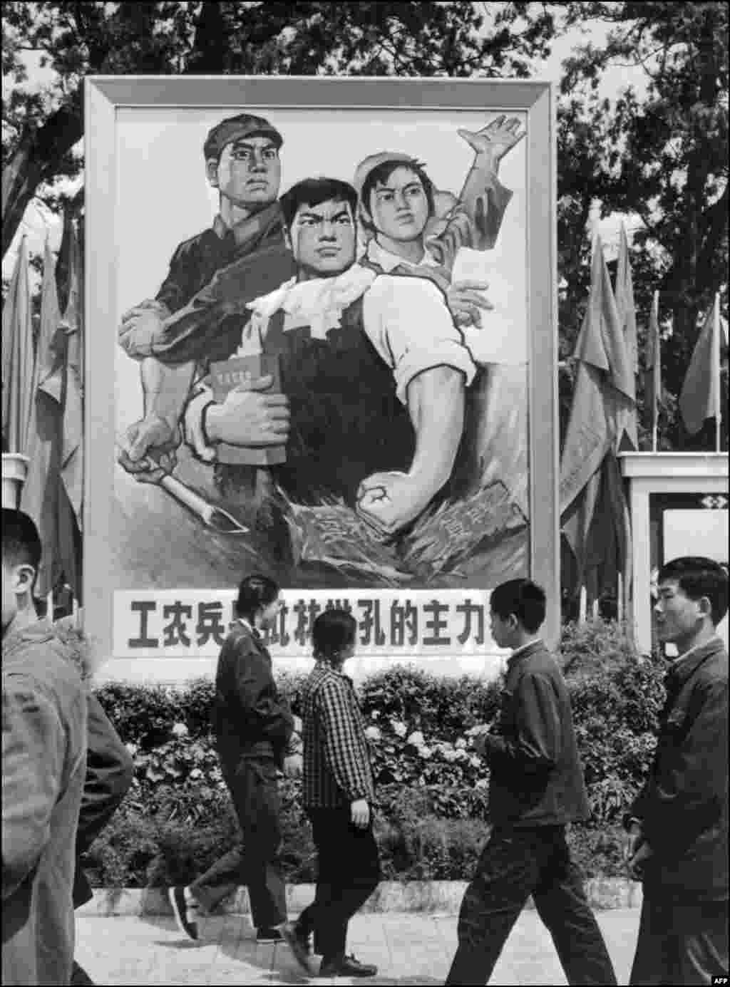 1974年5月,北京街头,人们走过宣传画,画上有工农兵和“工农兵是批林批孔的主力军”的口号。当时的中国当局把林彪和孔子连在一起批判,以便把林彪说成是极右,而非极左。有些人还提出批林批孔批周公的口号,指桑骂槐,明指周朝的周公,暗指周恩来。当时的红色洗脑的儿童歌曲唱道“ 叛徒林彪,孔老二,都是坏东西。嘴上讲仁义,肚里藏诡计,鼓吹‘克己复礼’,一心想复辟。红小兵齐上阵,大家都来狠狠批”。