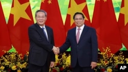 Perdana Menteri China Li Qiang, kiri, dan Perdana Menteri Vietnam Pham Minh Chinh berjabat tangan sebelum pertemuan di Hanoi, 13 Oktober 2024. (Duong Van Giang/VNA via AP)