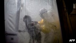 Des agents de la santé aident un patient à se coucher sur son lit au centre de traitement de Médecins sans frontière, Butembo, 3 novembre 2018.