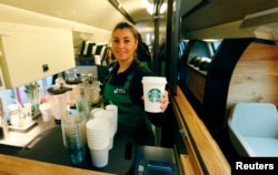 Seorang karyawan Starbucks memegang secangkir kopi di sebuah gerai Starbucks di Zurich, Swiss (foto: ilustrasi).