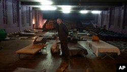 Muškarac čeka evakuaciju u zapadnu Ukrajinu dok stoji pored kreveta u gradskom pozorištu gde se prihvataju izbeglice koje beže od ruske ofanzive u regionu Donjecka, u Pavlogradu, Dnjepropetrovska oblast, Ukrajina, 12. decembar 2024.