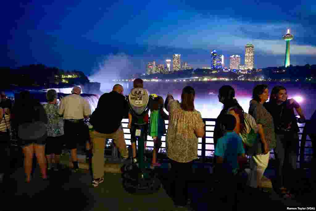 A magenta-illuminated Niagara Falls brightens the night sky. (R. Taylor/VOA)