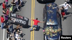 Seorang pelayat memegang spanduk berusaha menyentuh mobil yang mengangkut peti jenazah Muhammad Ali selama prosesi pemakaman legendaris tinju dunia tersebut di Louisville, Kentucky (10/6).