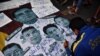 FILE - A protester writes pro-democracy messages on images of Thailand's Prime Minister Prayut Chan-ocha and top Thai generals during an anti-government rally in Bangkok, Feb. 20, 2021.